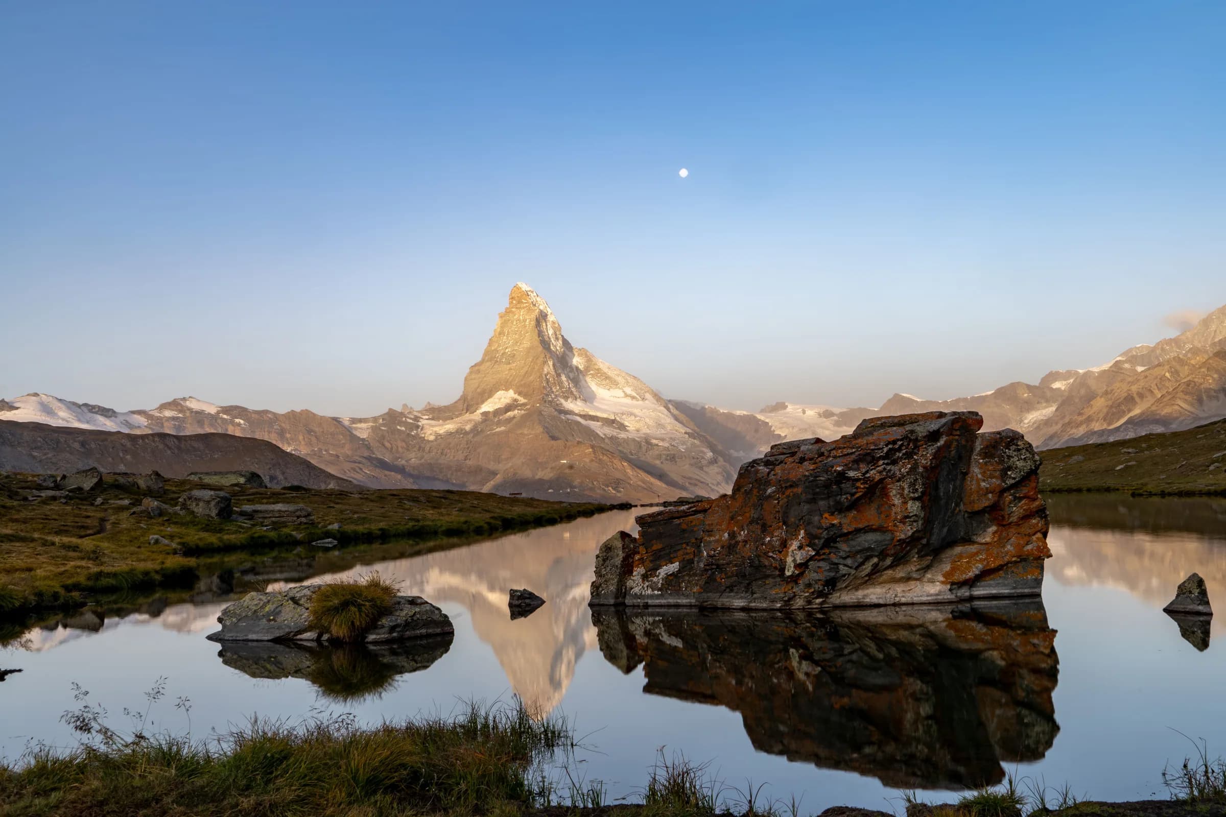 A still alpine lake mirroring the mountains at dawn, Switzerland