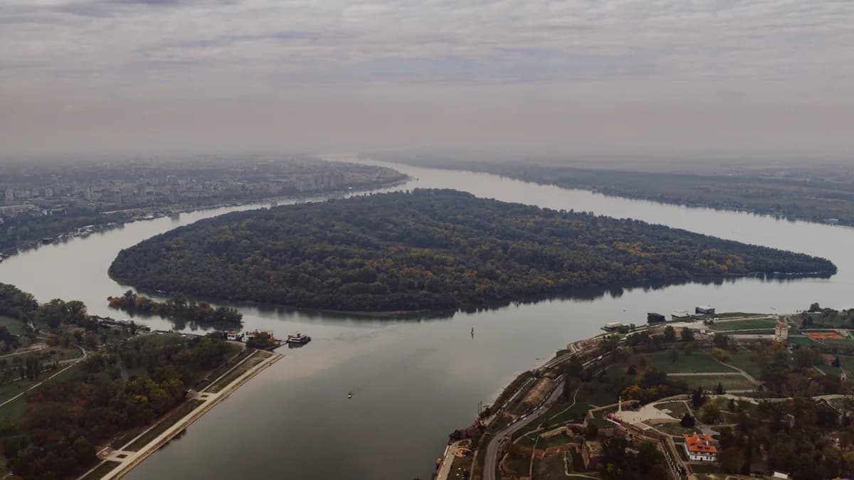 Stunning aerial shot of the river bend in Belgrade, Serbia, showcasing lush greenery and cityscape.