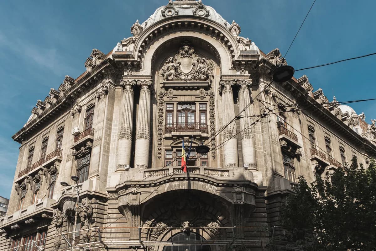 Captivating architecture of a historic building in Bucharest, showcasing classical details under a clear blue sky.