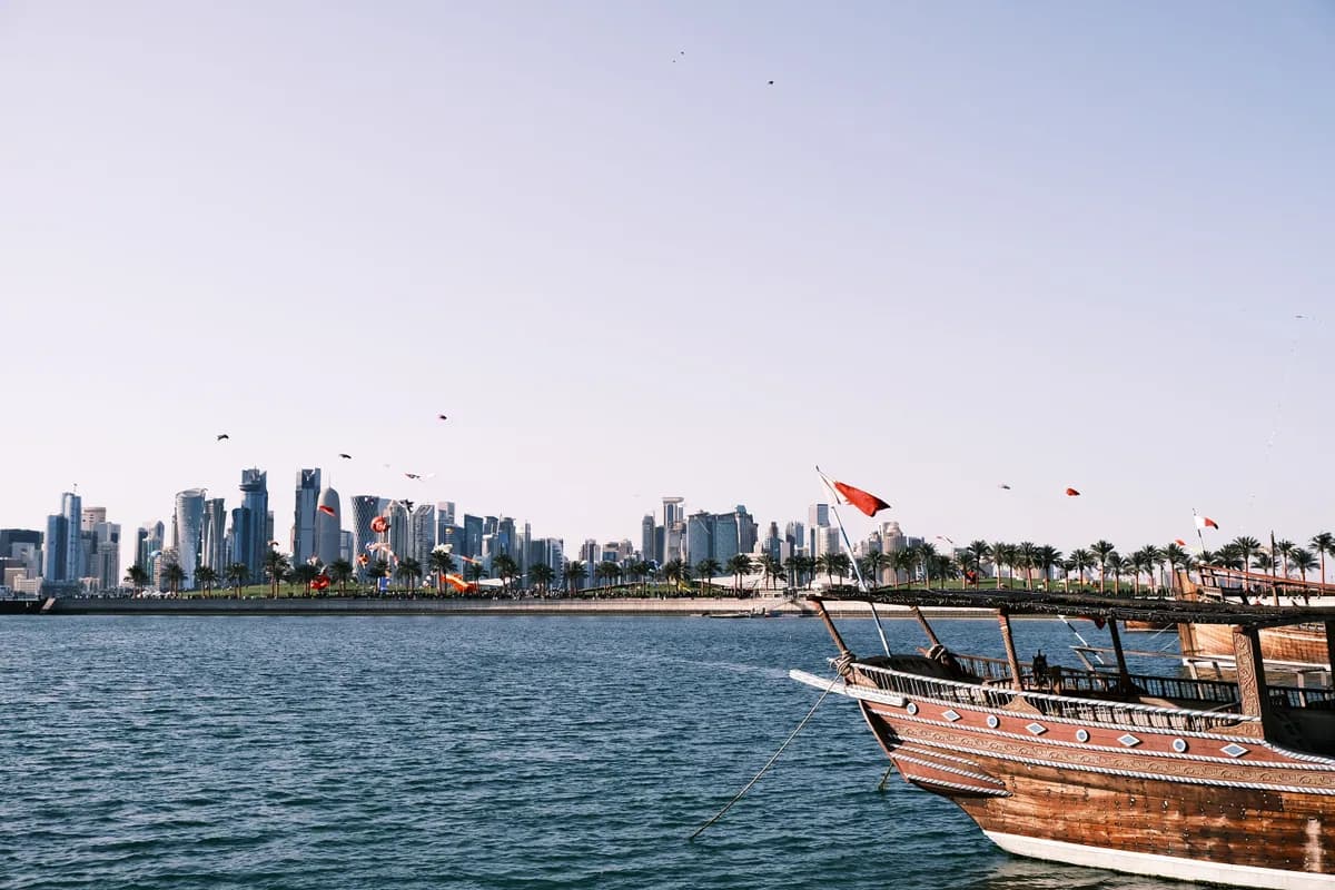 View of Doha skyline with a traditional dhow boat on the waterfront.