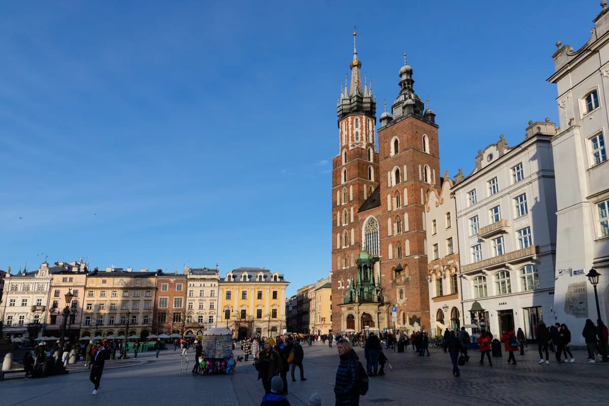Daytime view of St. Mary's Basilica in Krakow's Main Market Square, under clear blue skies.